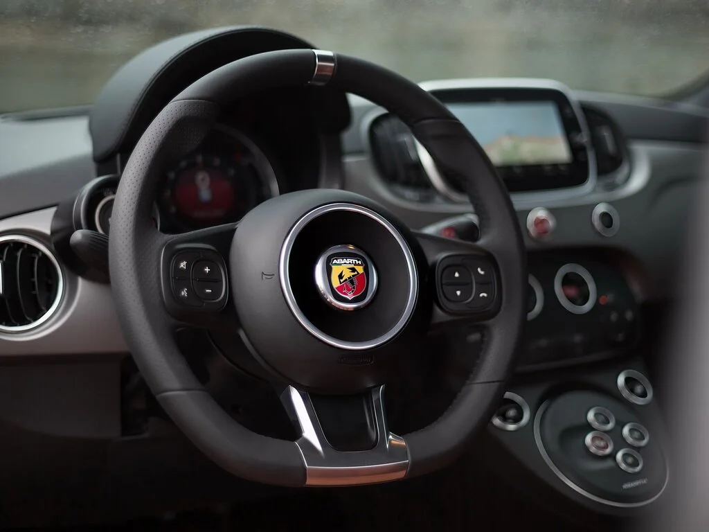Фото Abarth 595 (2022) — руль. Обод, спицы и кнопки на руле крупным планом Abarth 595 (2022) — руль