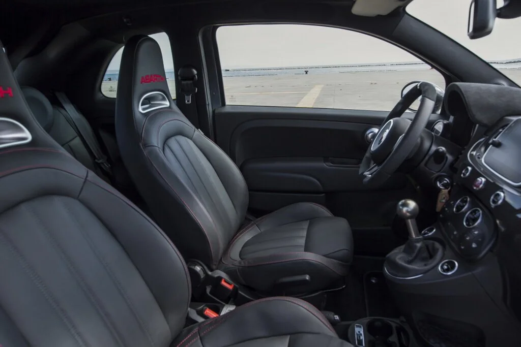 Фото Abarth 695 (2024) — интерьер, фото 2. Салон целиком: как расставлены кресла и что под рукой у водителя Abarth 695 (2024) — интерьер, фото 2