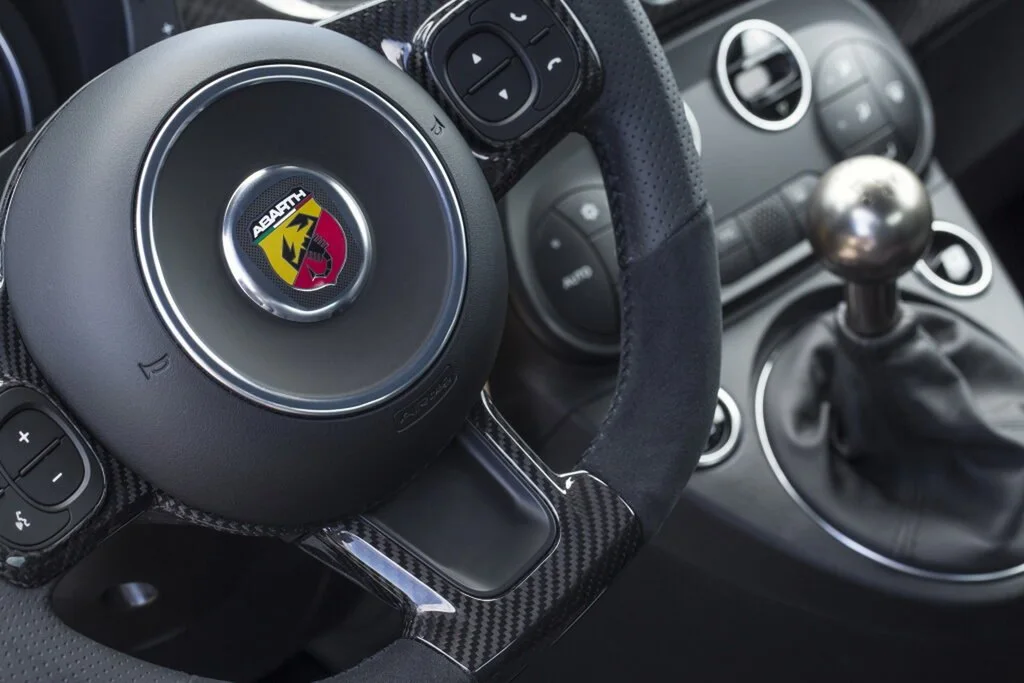 Фото Abarth 695 (2024) — руль. Обод, спицы и кнопки на руле крупным планом Abarth 695 (2024) — руль