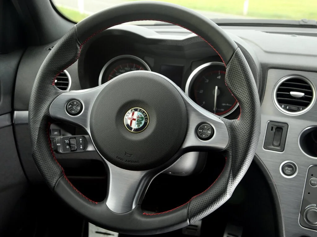 Фото Alfa Romeo 159 (2009) — руль. Обод, спицы и кнопки на руле крупным планом Alfa Romeo 159 (2009) — руль