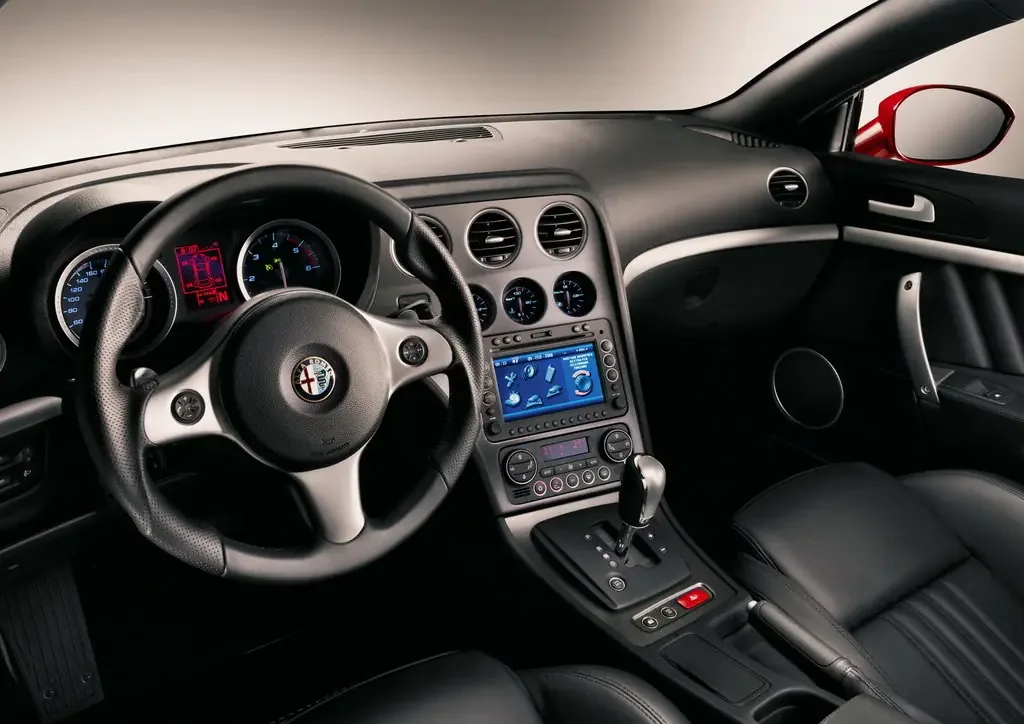 Фото Alfa Romeo Brera (2010) — интерьер. Общий план салона: панель, консоль и передние кресла Alfa Romeo Brera (2010) — интерьер