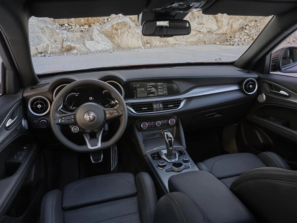 Фото Alfa Romeo Stelvio (2023) — интерьер. Общий план салона: панель, консоль и передние кресла Alfa Romeo Stelvio (2023) — интерьер