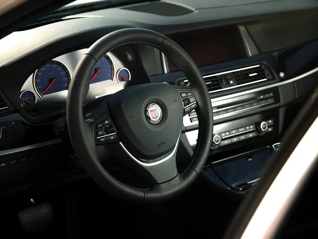 Фото Alpina D5 (2017) — руль. Обод, спицы и кнопки на руле крупным планом Alpina D5 (2017) — руль