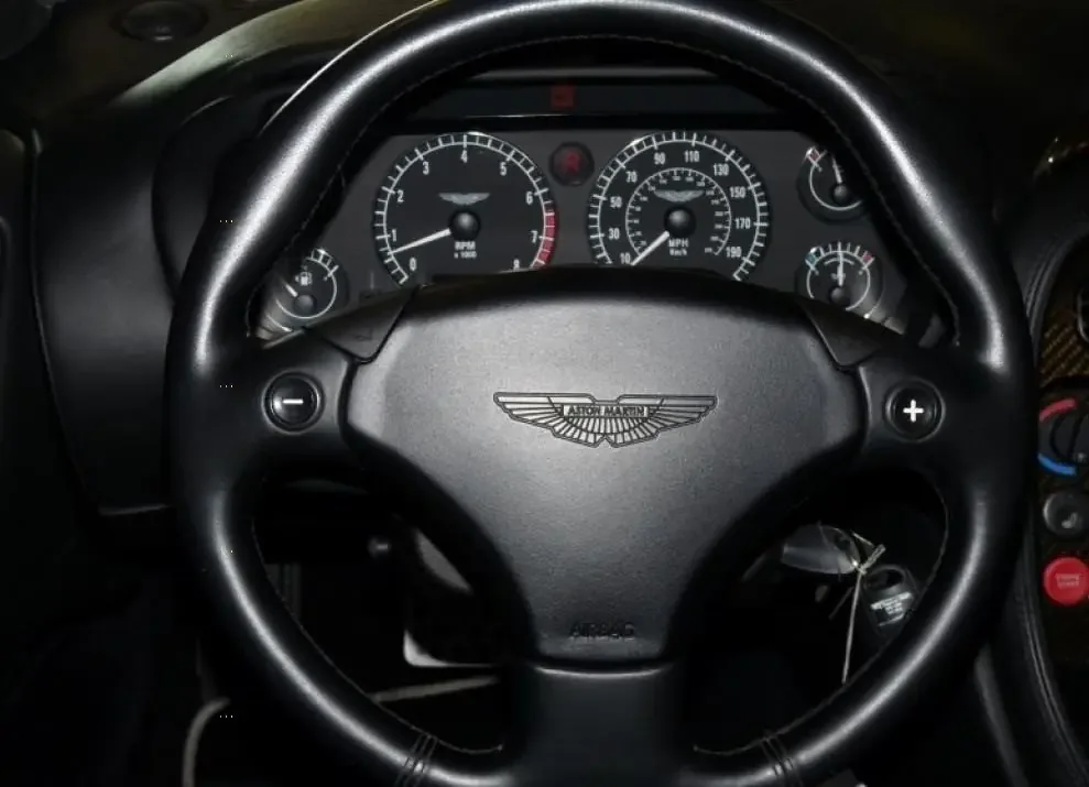 Фото Aston Martin DB7 (2003) — руль. Обод, спицы и кнопки на руле крупным планом Aston Martin DB7 (2003) — руль