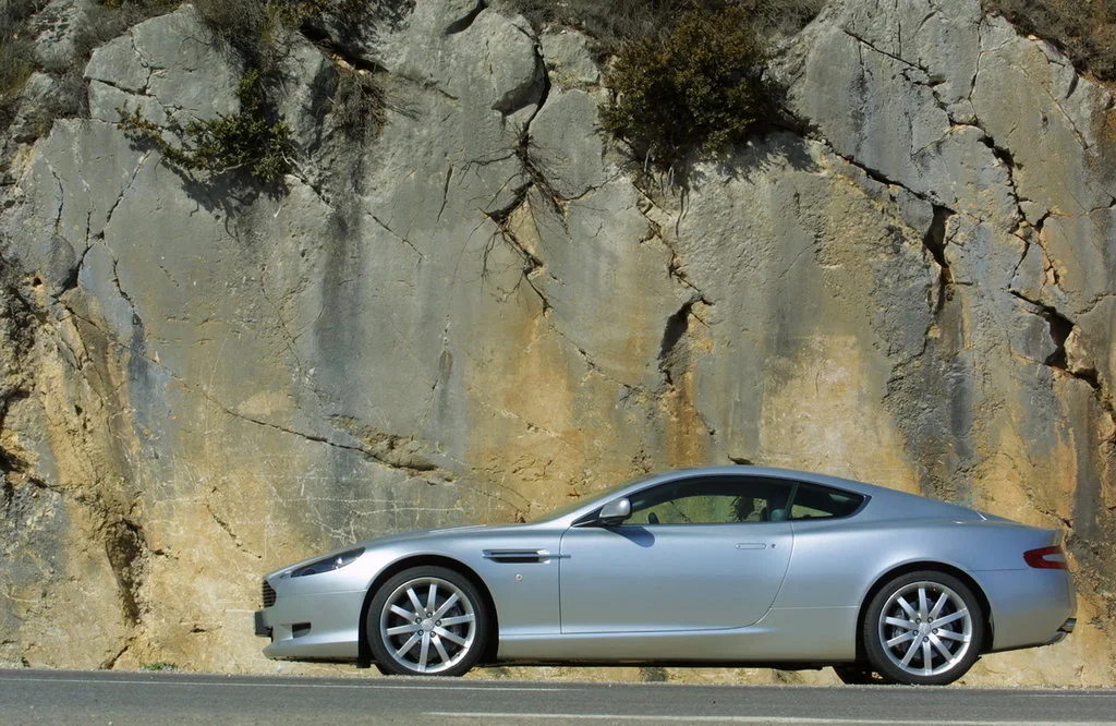 Фото Aston Martin DB9 (2016) — вид сбоку, фото 3. Профиль в движении: пропорции кузова на ходу Aston Martin DB9 (2016) — вид сбоку, фото 3
