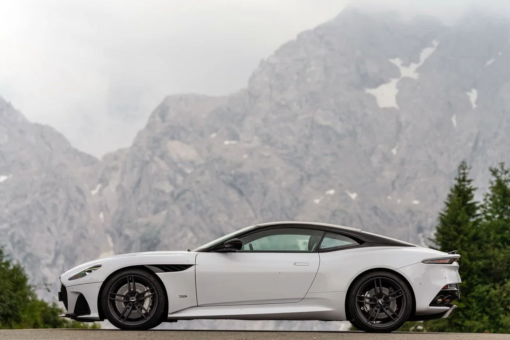 Фото Aston Martin DBS (2022) — вид сбоку, фото 3. Профиль в движении: пропорции кузова на ходу Aston Martin DBS (2022) — вид сбоку, фото 3