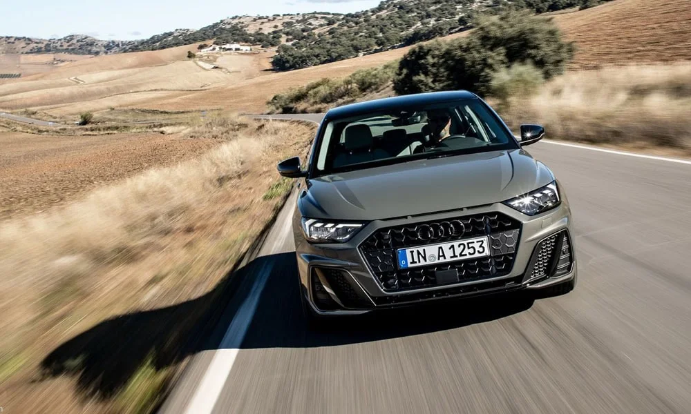 Фото Audi A1 Sportback — вид спереди, фото 6. Кузов в сером цвете: рисунок оптики и решётки задаёт узнаваемое «лицо» модели. Рисунок ходовых огней — подпись модели, по нему её узнают в потоке Audi A1 Sportback — вид спереди, фото 6