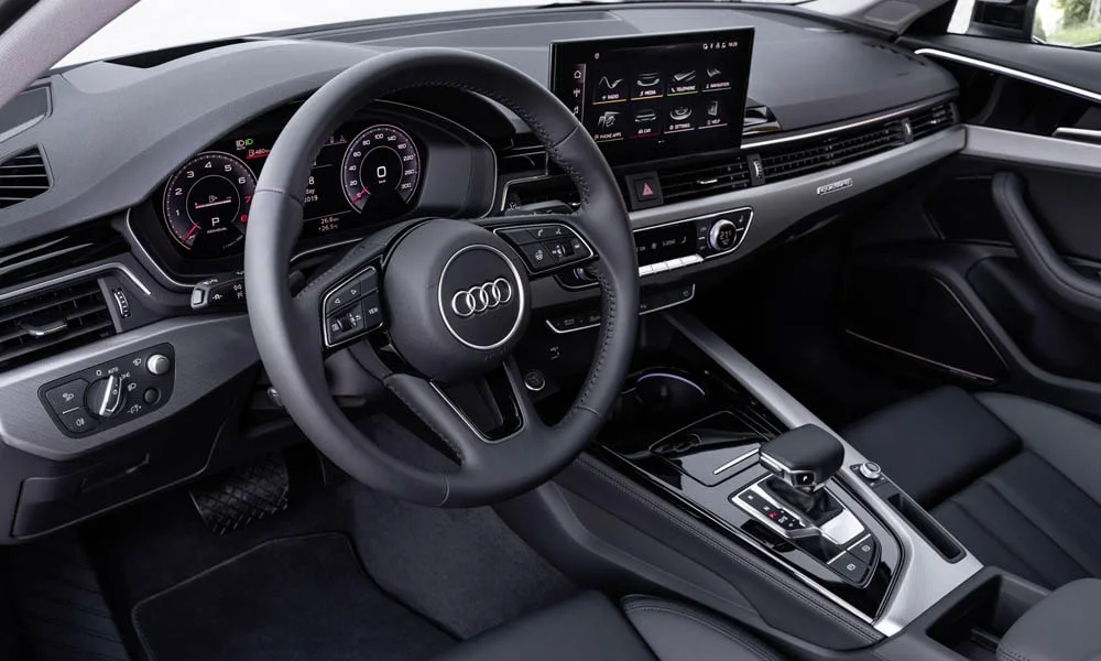 Фото Audi A4 — передняя панель, фото 3. Панель в тёмной отделке — видна компоновка экранов и органов управления. Минимум физических кнопок — ставка на экранное управление Audi A4 — передняя панель, фото 3