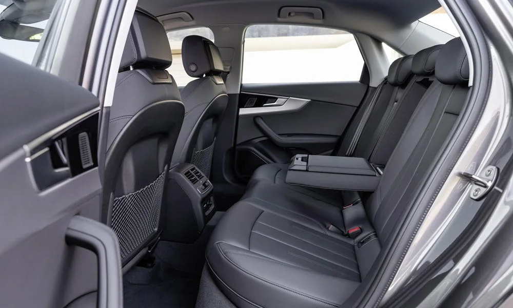 Фото Audi A4 — задние сиденья, фото 2. Посадка второго ряда: подголовники и подлокотник. Плоский пол упрощает посадку втроём Audi A4 — задние сиденья, фото 2