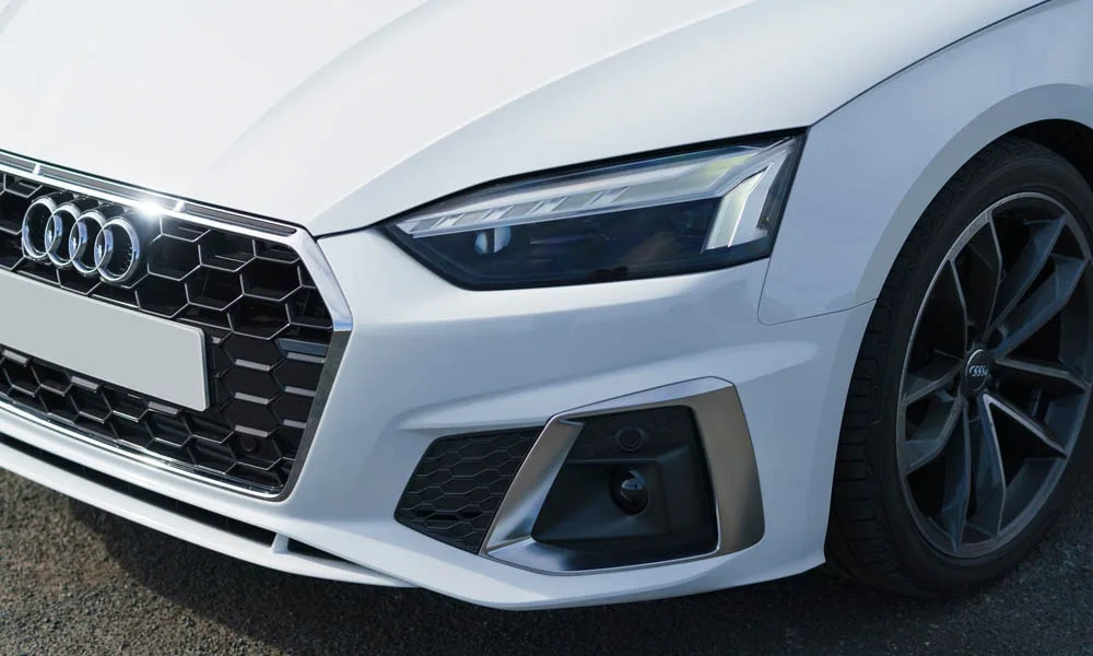 Фото Audi A5 — вид спереди, фото 12. Передок в белом исполнении — крупная светотехника и выразительный бампер. Рисунок ходовых огней — подпись модели, по нему её узнают в потоке Audi A5 — вид спереди, фото 12