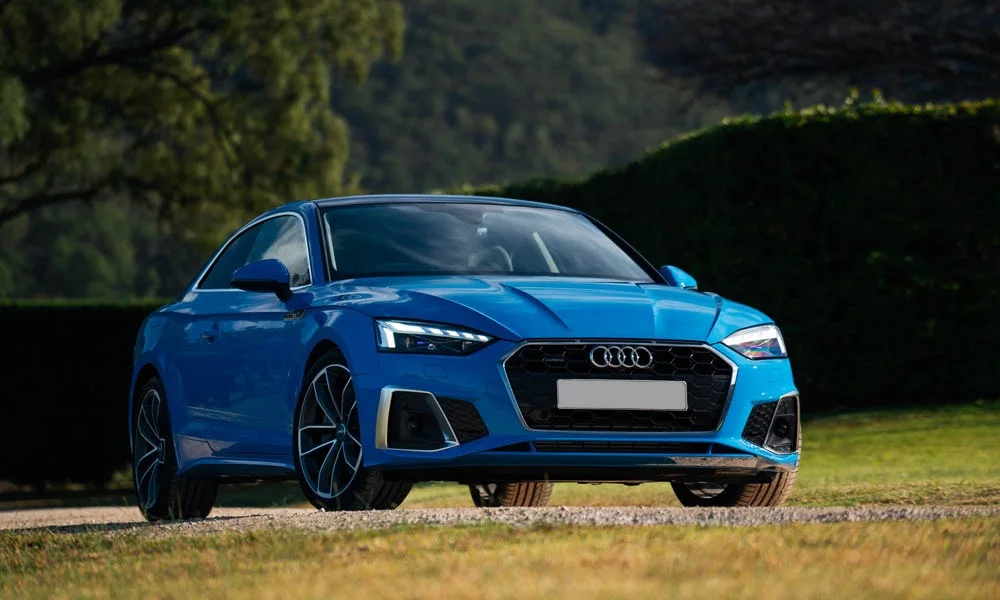 Фото Audi A5 — вид спереди, фото 16. Кузов в синем цвете: рисунок оптики и решётки задаёт узнаваемое «лицо» модели. Рисунок ходовых огней — подпись модели, по нему её узнают в потоке Audi A5 — вид спереди, фото 16