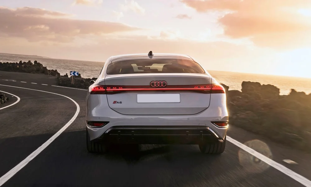 Фото Audi A6 Sportback e-tron (2024) — вид сзади, фото 4. Белый кузов сзади — фонари и бампер определяют ночной образ модели Audi A6 Sportback e-tron (2024) — вид сзади, фото 4