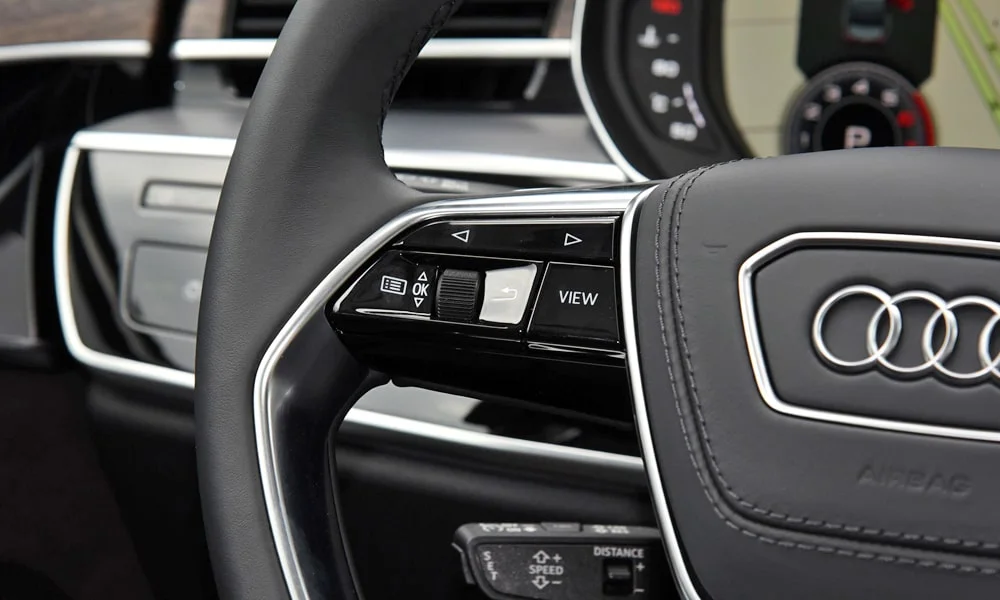 Фото Audi A8 L (2024) — руль, фото 2. Обшивка обода и компоновка спиц крупным планом. Клавиши на спицах управляют медиа, круизом и ассистентами — руки остаются на руле Audi A8 L (2024) — руль, фото 2