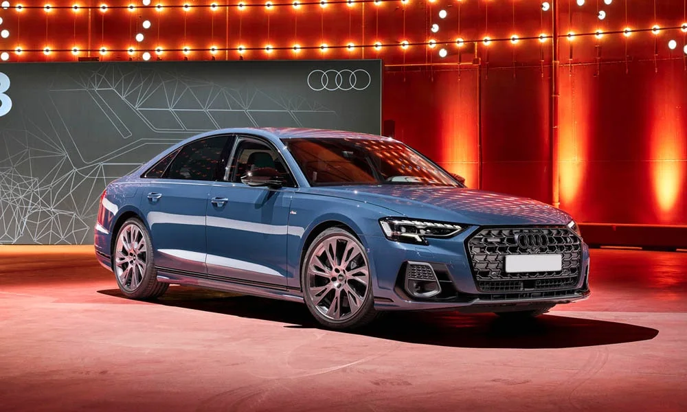 Фото Audi A8 (2024) — вид спереди, фото 8. Кузов в синем цвете: рисунок оптики и решётки задаёт узнаваемое «лицо» модели. Рисунок ходовых огней — подпись модели, по нему её узнают в потоке Audi A8 (2024) — вид спереди, фото 8