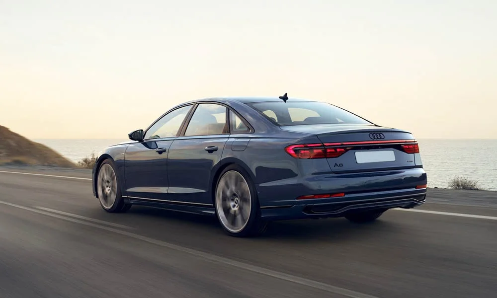 Фото Audi A8 (2024) — вид сзади, фото 8. Линия крыши, стойки и задняя дверь в синем исполнении. Насадки выхлопа или их имитация внизу бампера различают версии Audi A8 (2024) — вид сзади, фото 8