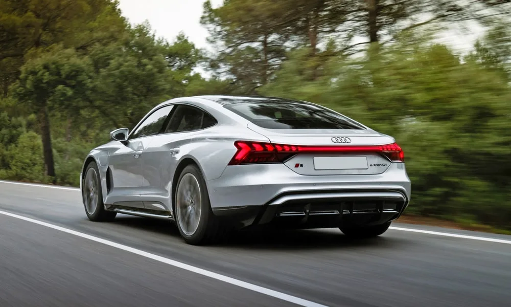 Фото Audi e-tron GT (2024) — вид сзади, фото 6. Серебристый кузов сзади — фонари и бампер определяют ночной образ модели. Светодиодная полоса или раздельные секции — задняя оптика стала главным украшением кормы Audi e-tron GT (2024) — вид сзади, фото 6