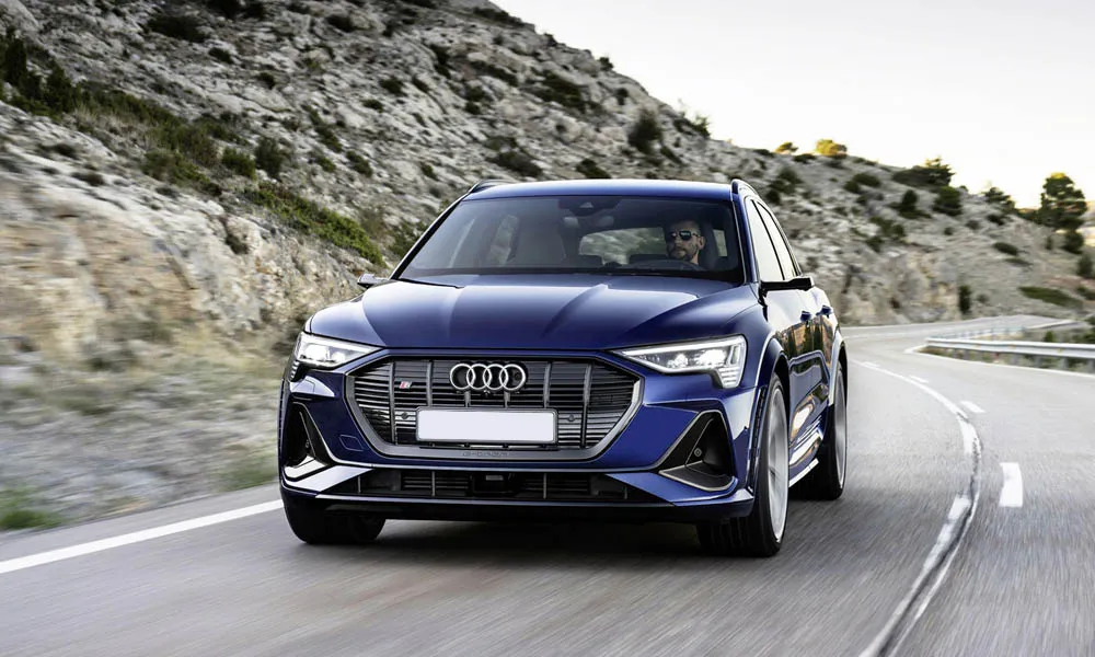 Фото Audi e-tron S — вид спереди, фото 9. Синий кузов, строгая симметрия оптики — базовый ракурс знакомства с дизайном. Рисунок ходовых огней — подпись модели, по нему её узнают в потоке Audi e-tron S — вид спереди, фото 9