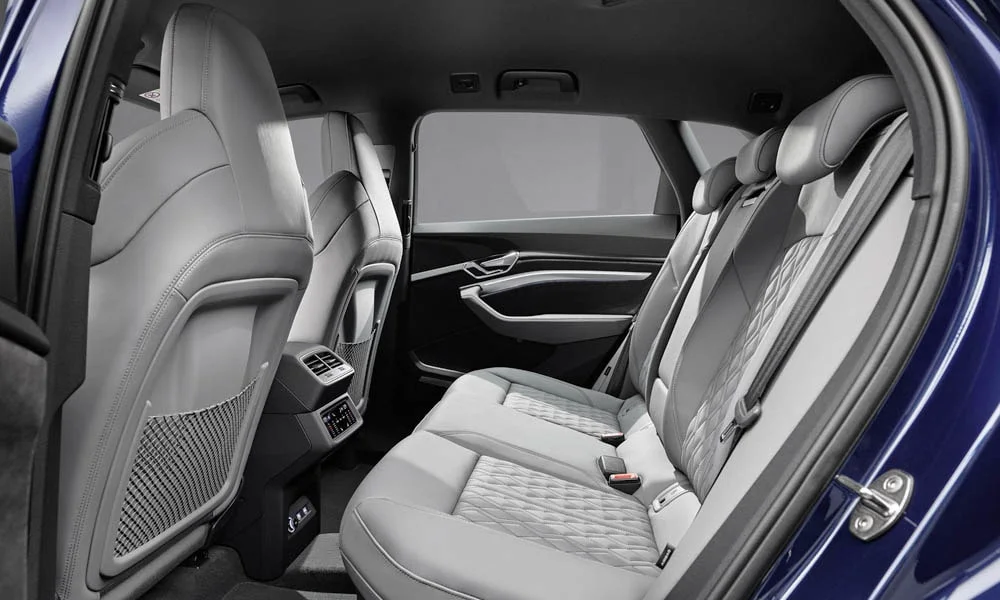 Фото Audi e-tron S — задние сиденья. Посадка второго ряда: подголовники и подлокотник. Спинки складываются под длинные грузы у большинства версий Audi e-tron S — задние сиденья