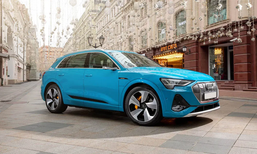 Фото Audi e-tron — вид спереди, фото 9. Синий кузов, строгая симметрия оптики — базовый ракурс знакомства с дизайном. Рисунок ходовых огней — подпись модели, по нему её узнают в потоке Audi e-tron — вид спереди, фото 9