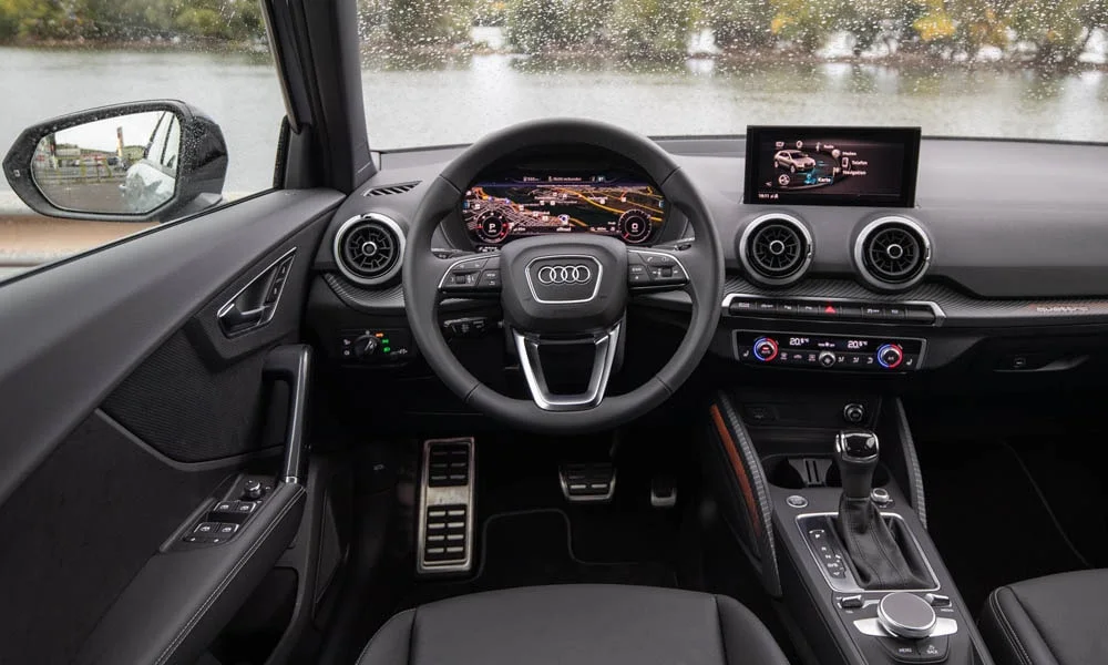 Фото Audi Q2 — передняя панель. Панель в тёмной отделке — видна компоновка экранов и органов управления. Мягкие материалы верхнего яруса и вставки задают уровень интерьера Audi Q2 — передняя панель