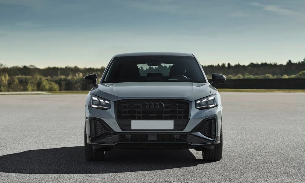 Фото Audi Q2 — вид спереди, фото 4. Серый кузов, строгая симметрия оптики — базовый ракурс знакомства с дизайном. Рисунок ходовых огней — подпись модели, по нему её узнают в потоке Audi Q2 — вид спереди, фото 4