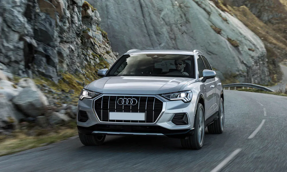 Фото Audi Q3 — вид спереди, фото 3. Серебристый кузов, строгая симметрия оптики — базовый ракурс знакомства с дизайном. Рисунок ходовых огней — подпись модели, по нему её узнают в потоке Audi Q3 — вид спереди, фото 3