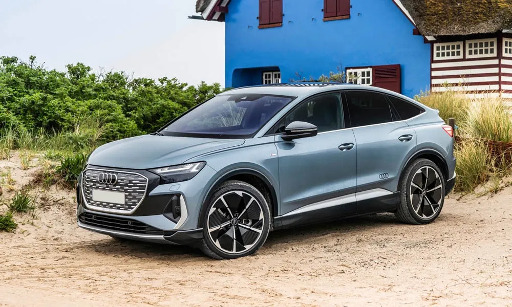Фото Audi Q4 e-tron Sportback (2024) — вид спереди, фото 5. Синий кузов, строгая симметрия оптики — базовый ракурс знакомства с дизайном. Дневные ходовые огни включаются автоматически с запуском Audi Q4 e-tron Sportback (2024) — вид спереди, фото 5