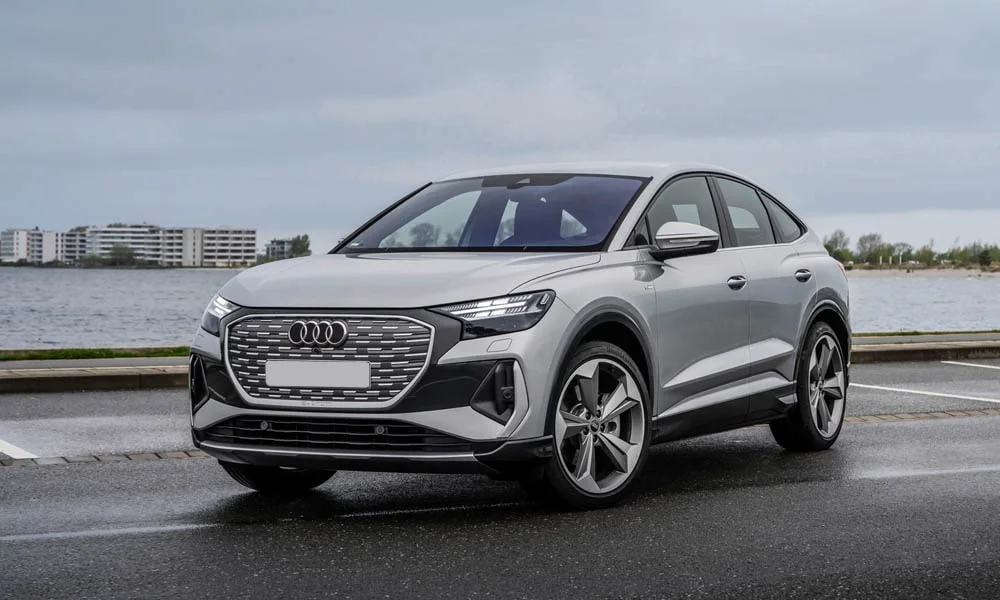 Фото Audi Q4 e-tron Sportback (2024) — вид спереди, фото 6. Кузов в серебристом цвете: рисунок оптики и решётки задаёт узнаваемое «лицо» модели. Дневные ходовые огни включаются автоматически с запуском Audi Q4 e-tron Sportback (2024) — вид спереди, фото 6