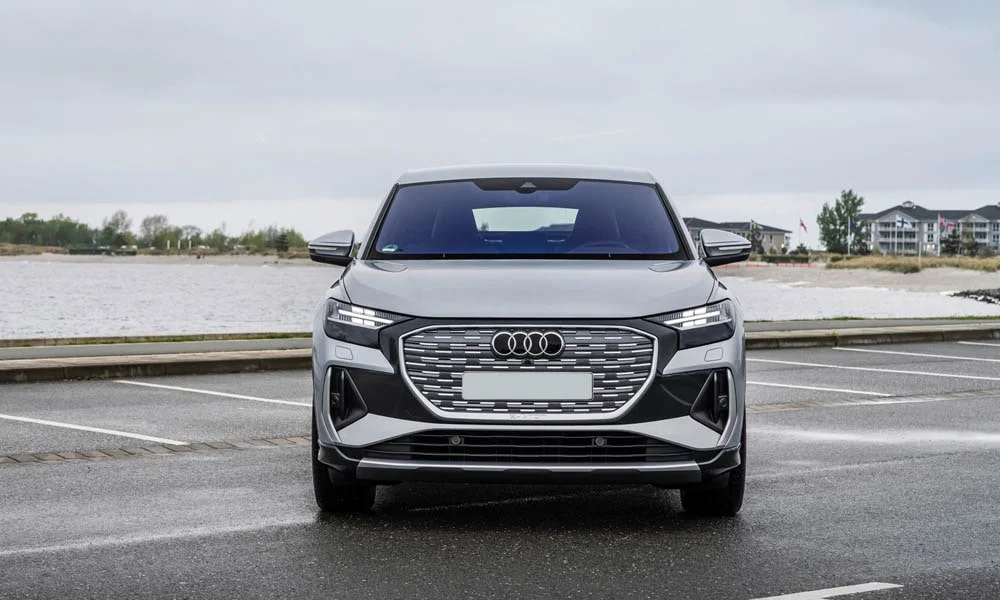 Фото Audi Q4 e-tron Sportback (2024) — вид спереди, фото 7. Передок в серебристом исполнении — крупная светотехника и выразительный бампер Audi Q4 e-tron Sportback (2024) — вид спереди, фото 7
