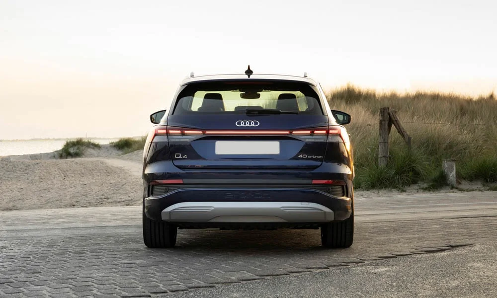 Фото Audi Q4 e-tron (2024) — вид сзади, фото 6. Корма в синем цвете: графика фонарей и пластика пятой двери. Насадки выхлопа или их имитация внизу бампера различают версии Audi Q4 e-tron (2024) — вид сзади, фото 6