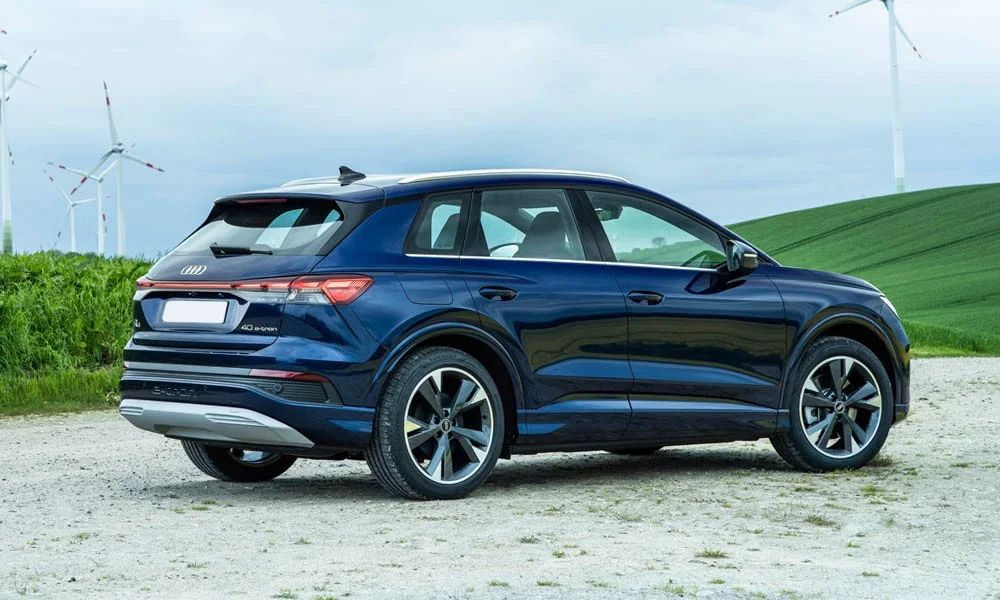 Фото Audi Q4 e-tron (2024) — вид сзади, фото 7. Синий кузов сзади — фонари и бампер определяют ночной образ модели. Насадки выхлопа или их имитация внизу бампера различают версии Audi Q4 e-tron (2024) — вид сзади, фото 7