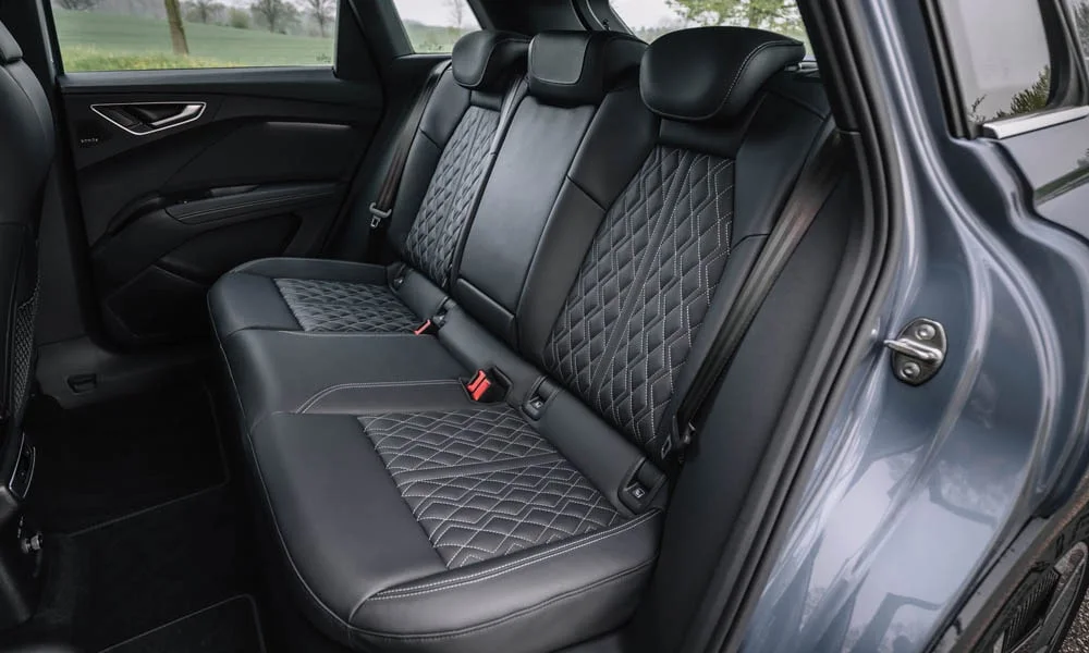 Фото Audi Q4 e-tron (2024) — задние сиденья. Посадка второго ряда: подголовники и подлокотник. Плоский пол упрощает посадку втроём Audi Q4 e-tron (2024) — задние сиденья