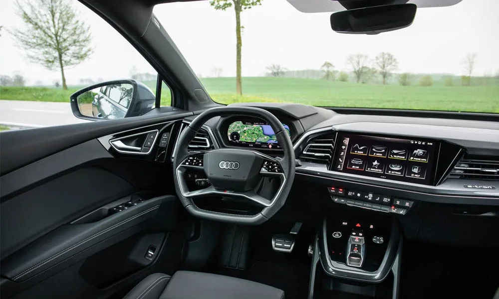 Фото Audi Q4 e-tron (2024) — руль. Обшивка обода и компоновка спиц крупным планом. Правильная посадка: руки на «9 и 3», приборы читаются поверх обода Audi Q4 e-tron (2024) — руль