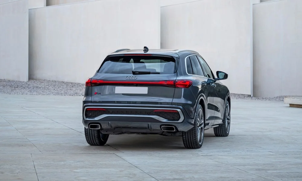 Фото Audi Q5 (2024) — вид сзади, фото 8. Корма в сером цвете: графика фонарей и пластика пятой двери. Светодиодная полоса или раздельные секции — задняя оптика стала главным украшением кормы Audi Q5 (2024) — вид сзади, фото 8