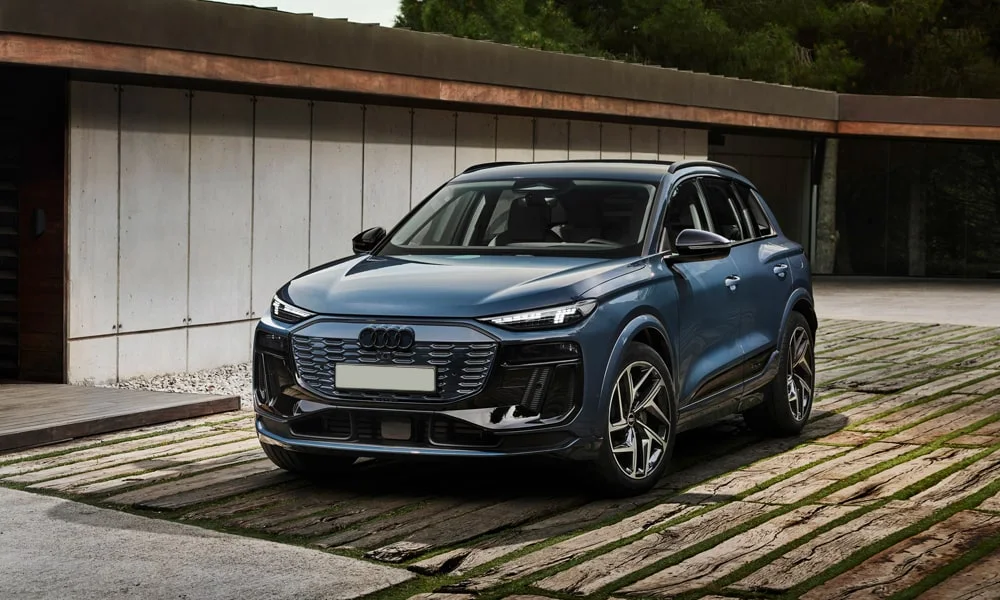 Фото Audi Q6 e-tron (2024) — вид спереди, фото 3. Кузов в синем цвете: рисунок оптики и решётки задаёт узнаваемое «лицо» модели. Дневные ходовые огни включаются автоматически с запуском Audi Q6 e-tron (2024) — вид спереди, фото 3