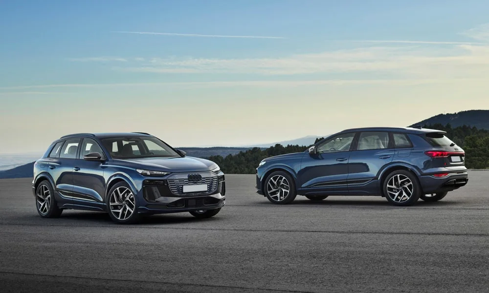 Фото Audi Q6 e-tron (2024) — вид спереди, фото 8. Синий кузов, строгая симметрия оптики — базовый ракурс знакомства с дизайном. Рисунок ходовых огней — подпись модели, по нему её узнают в потоке Audi Q6 e-tron (2024) — вид спереди, фото 8