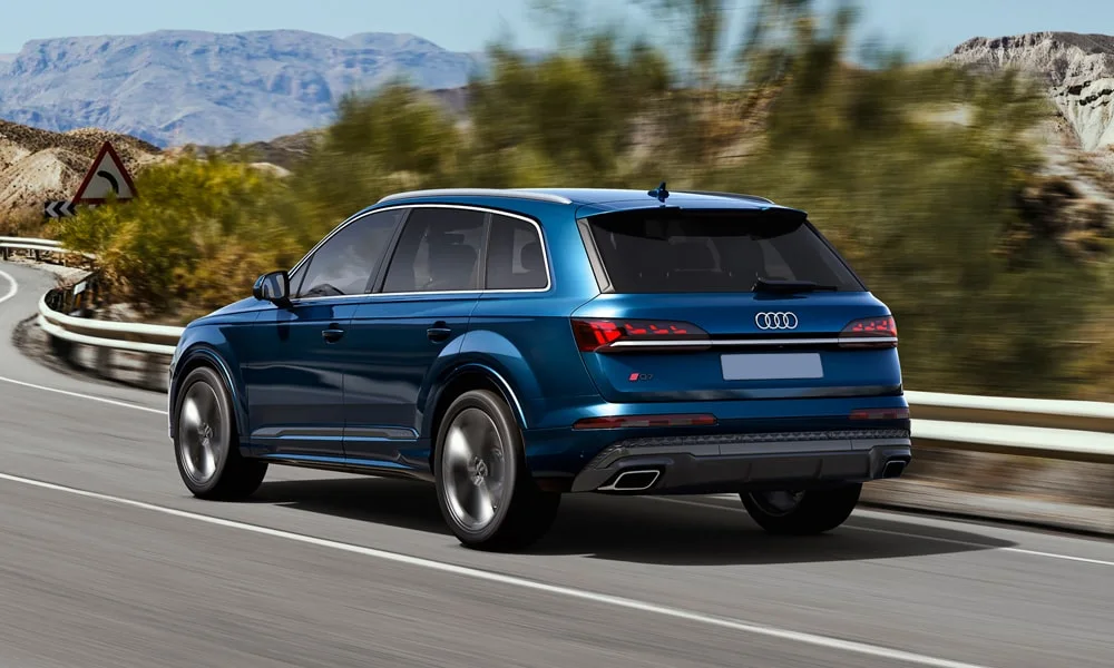 Фото Audi Q7 (2024) — вид сзади, фото 5. Корма в синем цвете: графика фонарей и пластика пятой двери. Светодиодная полоса или раздельные секции — задняя оптика стала главным украшением кормы Audi Q7 (2024) — вид сзади, фото 5