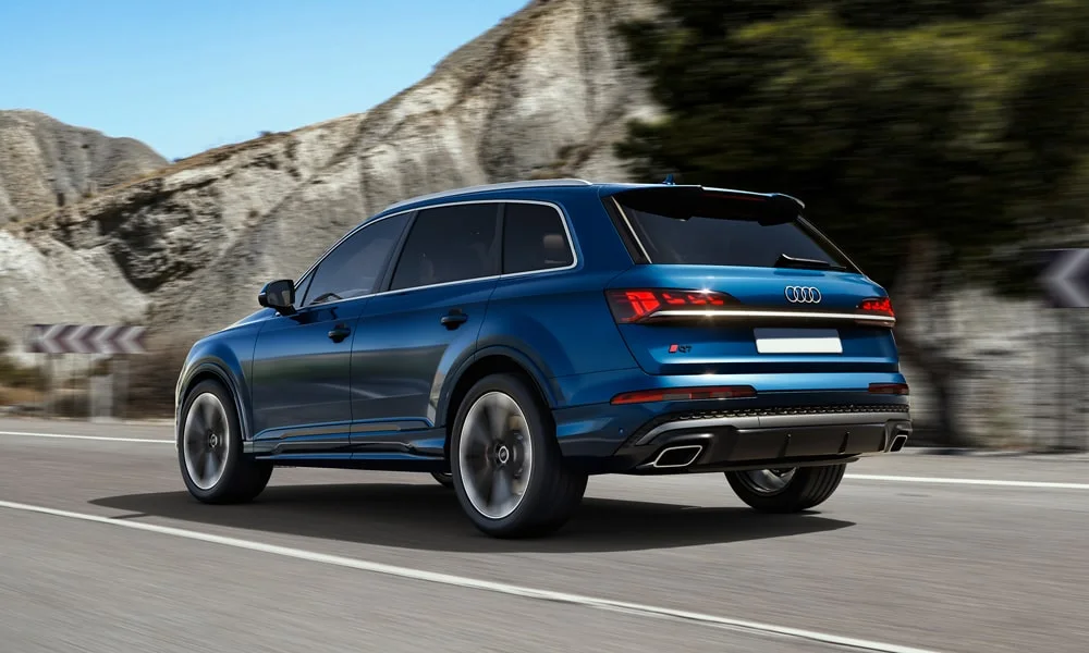 Фото Audi Q7 (2024) — вид сзади, фото 7. Линия крыши, стойки и задняя дверь в синем исполнении. Насадки выхлопа или их имитация внизу бампера различают версии Audi Q7 (2024) — вид сзади, фото 7