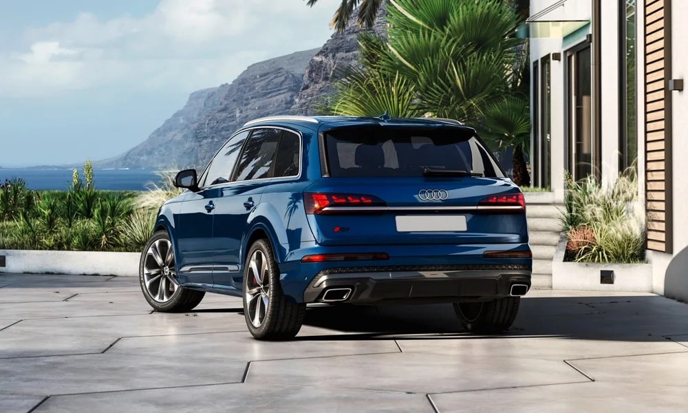 Фото Audi Q7 (2024) — вид сзади, фото 9. Корма в синем цвете: графика фонарей и пластика пятой двери. Насадки выхлопа или их имитация внизу бампера различают версии Audi Q7 (2024) — вид сзади, фото 9
