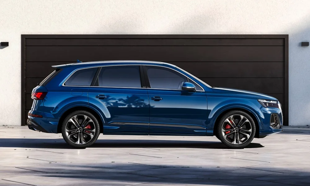 Фото Audi Q7 (2024) — вид сбоку, фото 2. Синий кузов в профиль — пропорции, высота посадки и дизайн дисков. Длинная база — простор второго ряда; короткие свесы упрощают парковку Audi Q7 (2024) — вид сбоку, фото 2