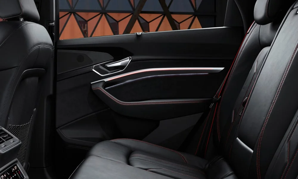 Фото Audi Q8 e-tron (2024) — дверная карта, фото 2. Внутренняя панель двери: сочетание материалов и компоновка управления в тёмной гамме. Решётка динамика в двери — часть штатной акустики Audi Q8 e-tron (2024) — дверная карта, фото 2