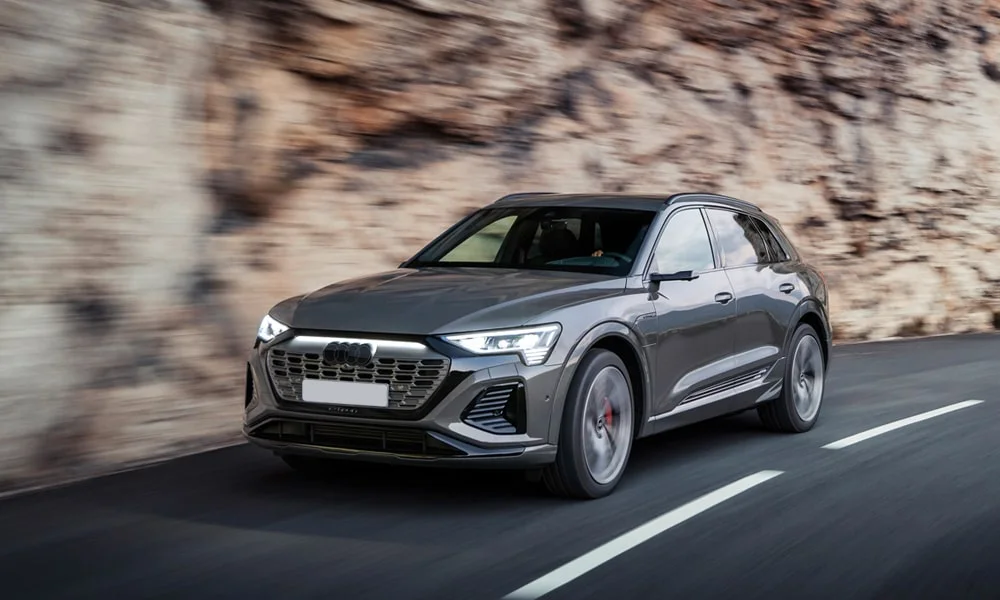 Фото Audi Q8 e-tron (2024) — вид спереди, фото 4. Кузов в сером цвете: рисунок оптики и решётки задаёт узнаваемое «лицо» модели Audi Q8 e-tron (2024) — вид спереди, фото 4
