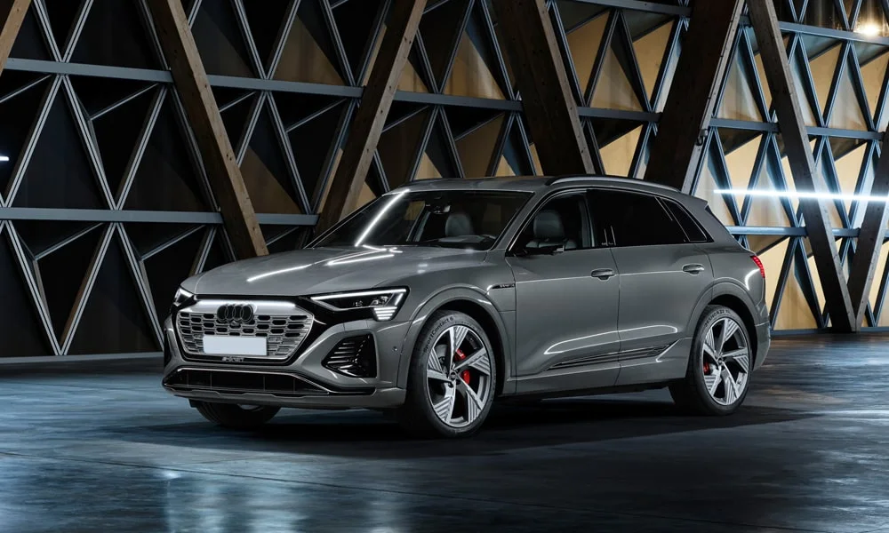 Фото Audi Q8 e-tron (2024) — вид спереди, фото 10. Серый кузов, строгая симметрия оптики — базовый ракурс знакомства с дизайном. Дневные ходовые огни включаются автоматически с запуском Audi Q8 e-tron (2024) — вид спереди, фото 10