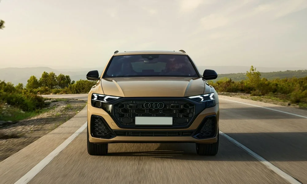 Фото Audi Q8 (2024) — вид спереди, фото 4. Кузов в золотистом цвете: рисунок оптики и решётки задаёт узнаваемое «лицо» модели. Дневные ходовые огни включаются автоматически с запуском Audi Q8 (2024) — вид спереди, фото 4
