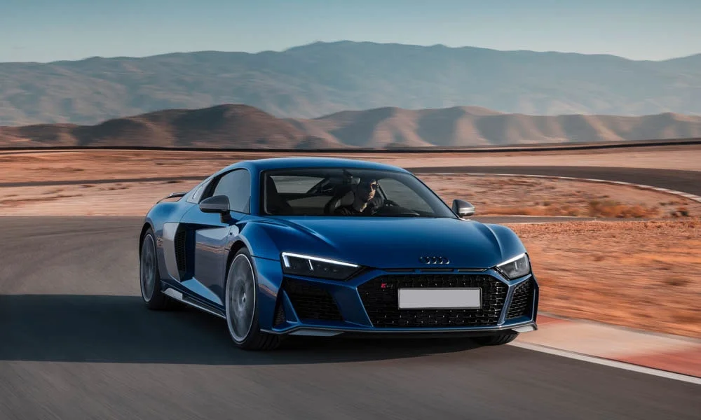 Фото Audi R8 (2024) — вид спереди, фото 9. Передок в синем исполнении — крупная светотехника и выразительный бампер. Дневные ходовые огни включаются автоматически с запуском Audi R8 (2024) — вид спереди, фото 9