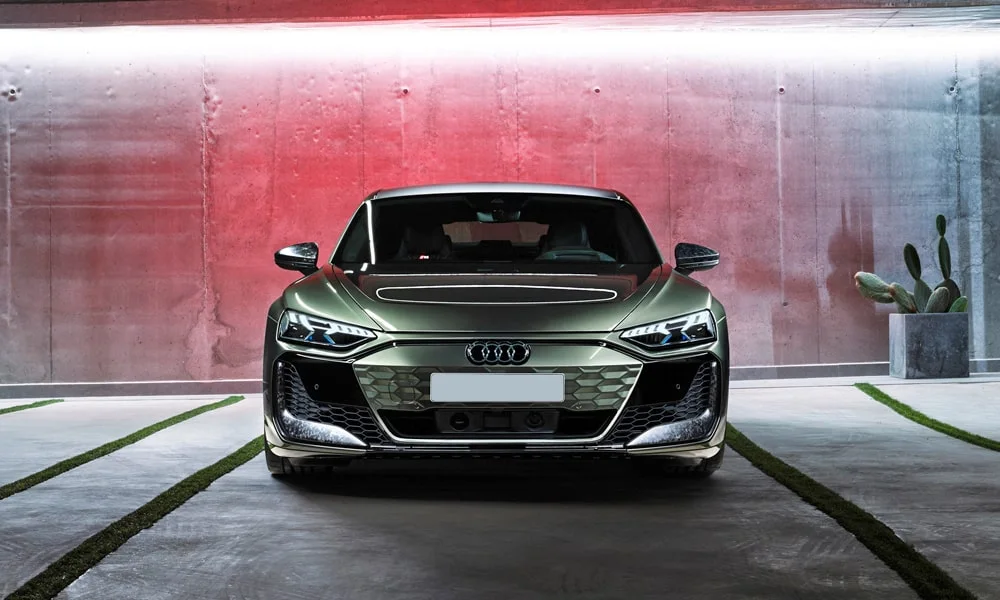 Фото Audi RS e-tron GT (2024) — вид спереди, фото 7. Передок в зелёном исполнении — крупная светотехника и выразительный бампер. Рисунок ходовых огней — подпись модели, по нему её узнают в потоке Audi RS e-tron GT (2024) — вид спереди, фото 7