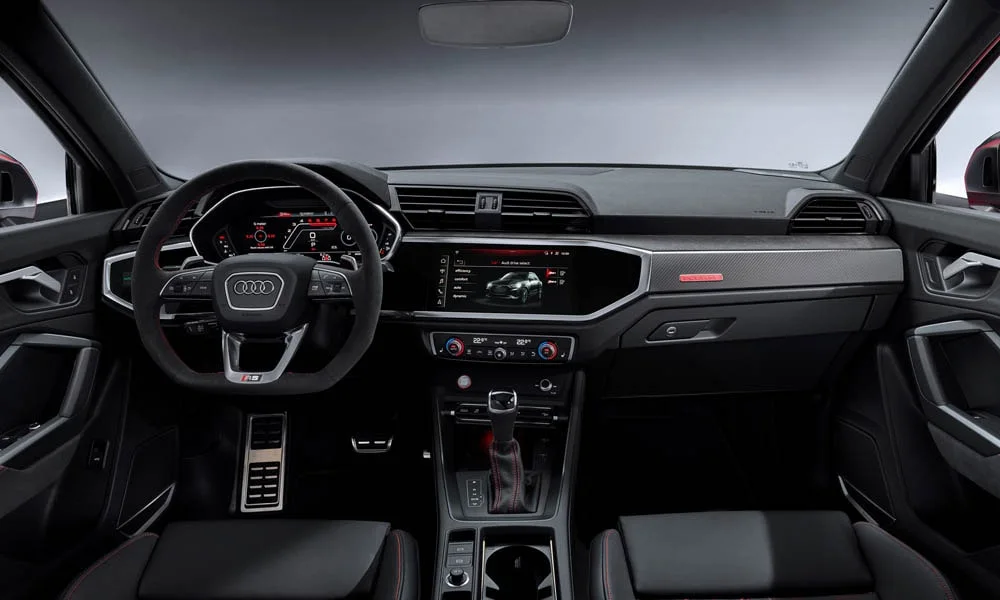 Фото Audi RS Q3 (2024) — передняя панель. Передняя панель в красно-чёрной отделке: расположение экранов и дефлекторов. Минимум физических кнопок — ставка на экранное управление Audi RS Q3 (2024) — передняя панель