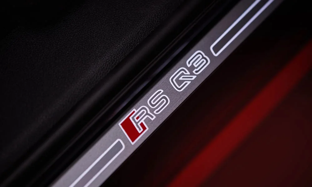 Фото Audi RS Q3 (2024) — дверная карта. Внутренняя панель двери: сочетание материалов и компоновка управления в красно-чёрной гамме Audi RS Q3 (2024) — дверная карта