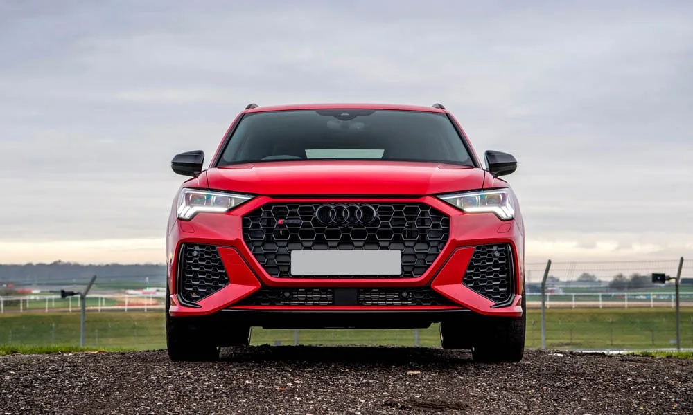 Фото Audi RS Q3 (2024) — вид спереди, фото 5. Передок в красном исполнении — крупная светотехника и выразительный бампер. Дневные ходовые огни включаются автоматически с запуском Audi RS Q3 (2024) — вид спереди, фото 5