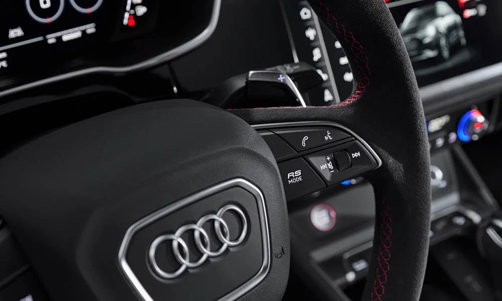 Фото Audi RS Q3 (2024) — руль. Обшивка обода и компоновка спиц крупным планом. Клавиши на спицах управляют медиа, круизом и ассистентами — руки остаются на руле Audi RS Q3 (2024) — руль